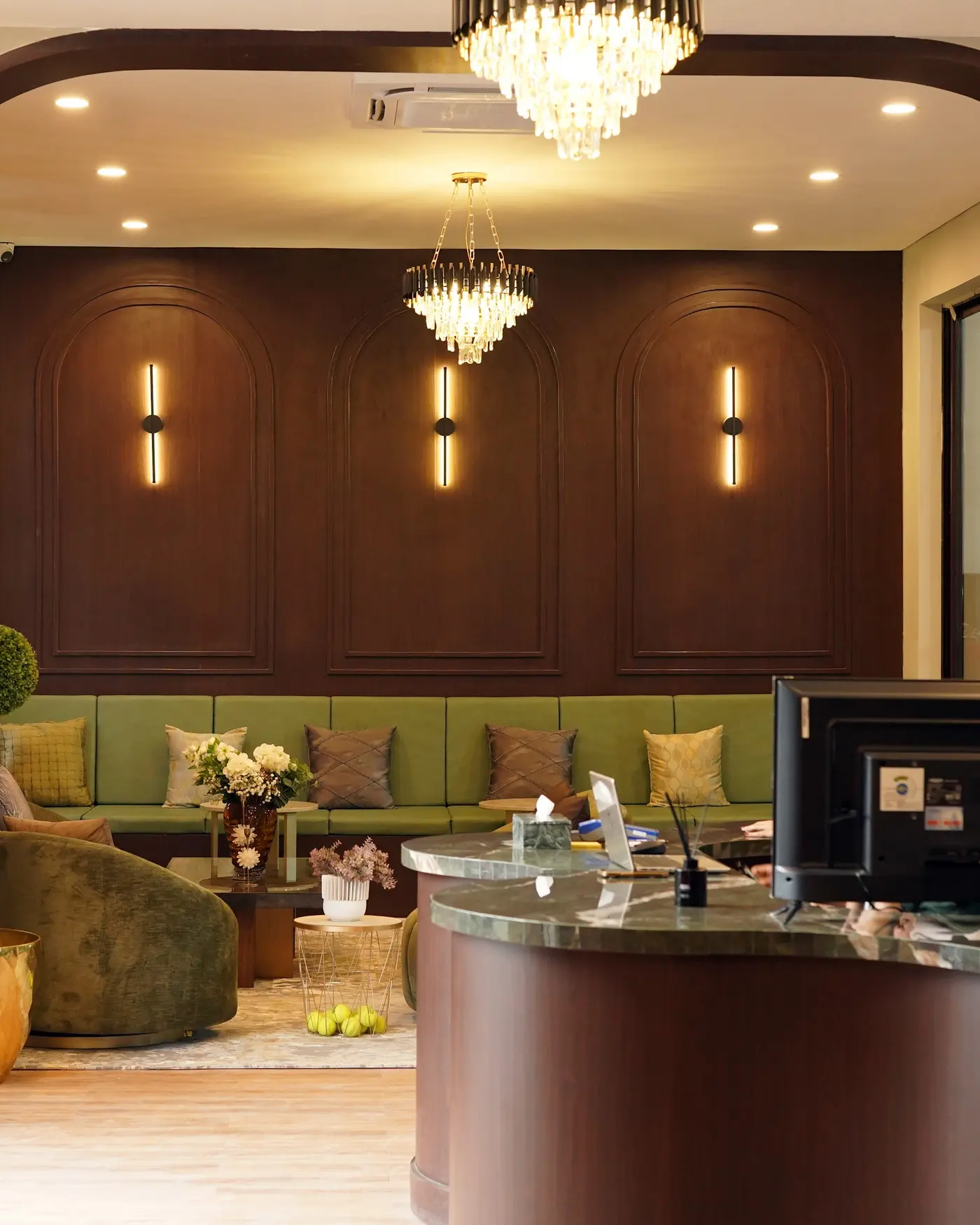 MOP Arena reception lounge with arched walnut panelling, chandeliers and green sofas