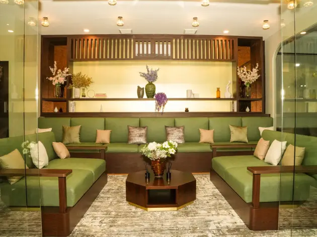 VIP lounge with green sofas, flowers and wood shelving